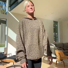 Model wearing a stylish leopard print hoodie, showcasing bold design and comfortable fit in a modern living space.