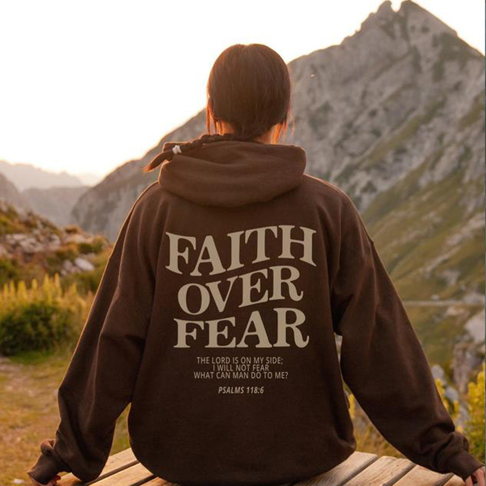 Faith Over Fear Hoodie worn outdoors, featuring a motivational design and scenic mountain backdrop.